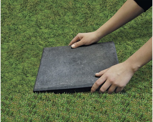 Une personne pose une dalle de jardin dans le jardin.