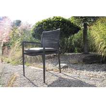 Gartenstuhl mit Armlehnen und Sitzkissen vor Grünpflanzen