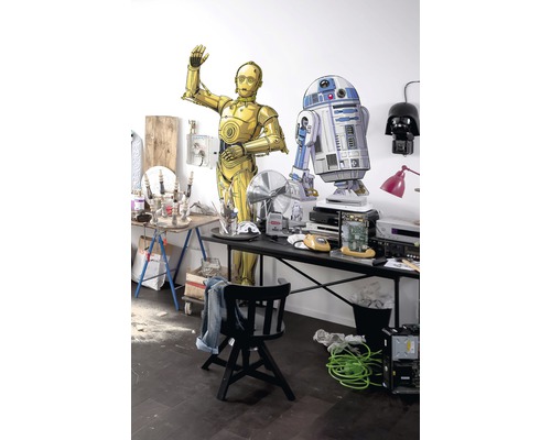 Scène avec des figurines C-3PO et R2-D2 sur une table avec divers objets.