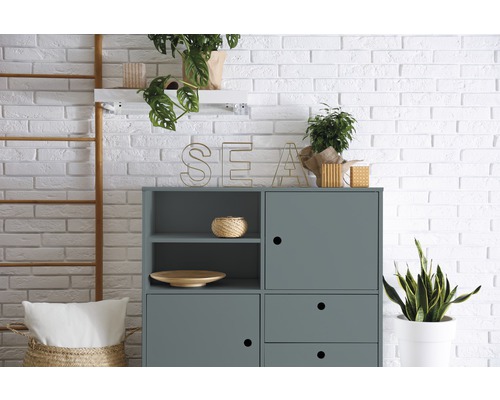 Grauer Schrank mit Regalen, Dekoration und Pflanzen vor einer Backsteinwand