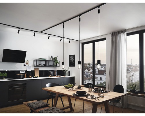 Helle Küche mit Esstisch, Stühlen und schwarzer Küchenzeile unter einer Schienenbeleuchtung