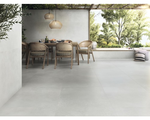 Terrasse mit Terrassenplatten, Esstisch und Stühlen unter einer Pergola