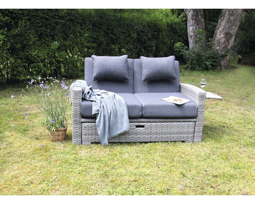 Scène de jardin avec canapé lounge deux places gris comprenant des coussins et une couverture à l''extérieur