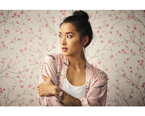 Frau mit Kimono vor Tapete mit Blütenmuster