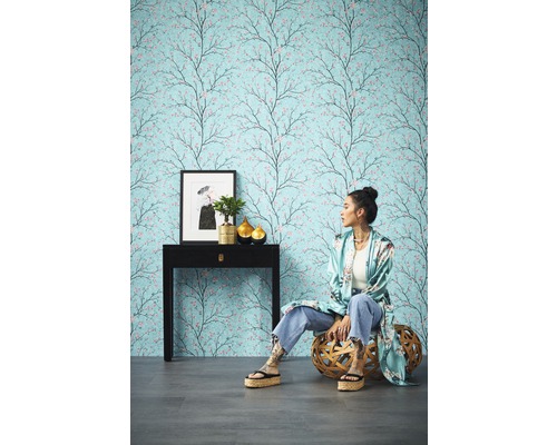 Raumansicht mit gemusterter Tapete mit Baumdesign, Konsole, Dekoration und sitzender Person
