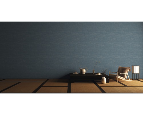 Salon avec papier peint bleu, table, service à thé, fauteuil et lampe