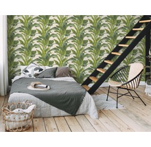 Schlafzimmer mit einer Wandtapete mit Pflanzenmotiven, Bett, Treppe und einem Stuhl.