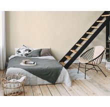 Schlafzimmer mit Bett, Leiter und Rattansessel auf Holzboden