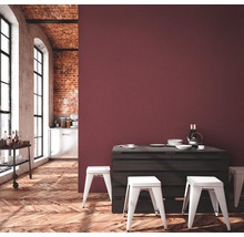 Pièce lumineuse avec parquet, mur en briques, chariot de bar, table à manger en palettes et tabourets blancs devant un mur