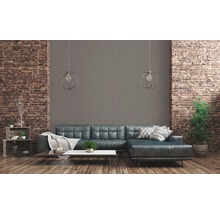 Wohnzimmer mit Sofa, Couchtisch und Dekoration vor einer Backsteinwand