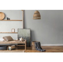 Wohnraum mit Holzregal, Korbmöbeln, Textilien und abstrakter Malerei