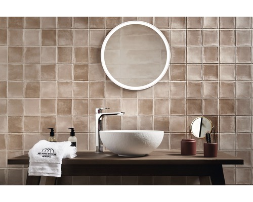 Helles Badezimmer mit braunen Fliesen, runder Spiegel und modernem Waschtisch