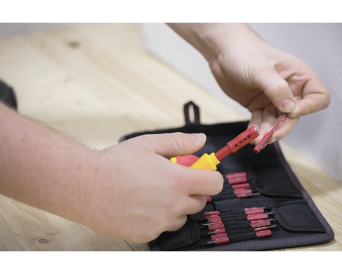 Person benutzt ein Abisolierwerkzeug zum Abisolieren eines Kabels vor Werkzeugtasche