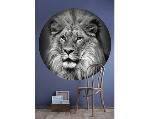 Dekoratives Wandtattoo mit Löwenmotiv, daneben ein Holzstuhl und ein Korb mit Bilderrahmen
