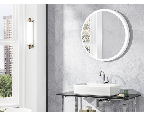 Badezimmer mit rundem Spiegel, Aufsatzwaschbecken und Wandleuchte.