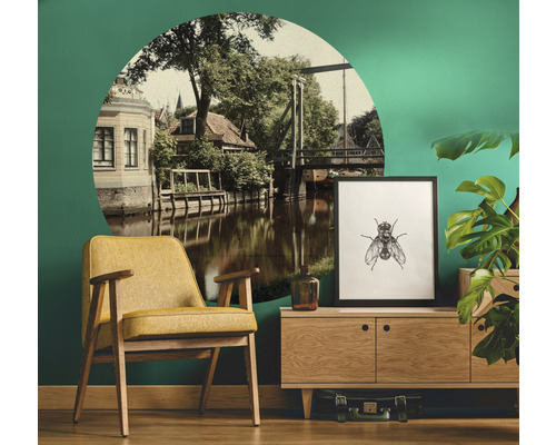 Wohnzimmer mit Sessel, Kommode, Zimmerpflanze, Dekoration und Wandtattoo mit Flusslandschaft