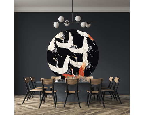 Salle à manger avec table, chaises, plafonnier et décoration murale ronde avec motifs de grues.