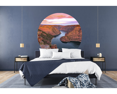 Schlafzimmer mit Bett, Nachttischen und runder Wanddekoration mit Berglandschaft