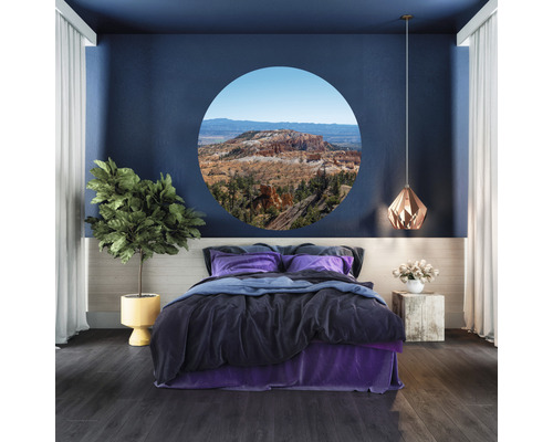 Schlafzimmer mit Bett, Zimmerpflanze, Lampe und runder Fensterattrappe mit Landschaftsmotiv