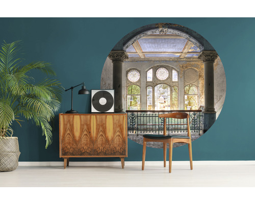 Wohnraum mit Kommode, Zimmerpflanze, Lampe, Schallplatte und Wandbild mit historischem Gebäude