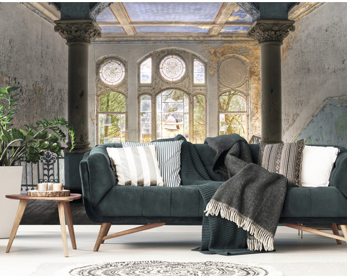 Salon avec canapé, coussins, couverture et papier peint mural avec motif architectural