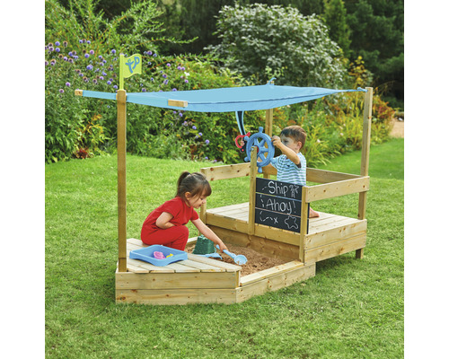 Holzsandkasten in Bootsform mit zwei Kindern, einem Sonnensegel und einem Steuerrad