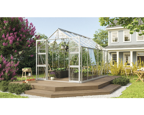 Gewächshaus Vitavia Olymp 9900 Einscheibensicherheitsglas 3 mm 257 x 386 cm silber Gewächshaus im Garten mit Pflanzen und Gartenmöbeln auf einer Holzterrasse vor einem Wohnhaus.