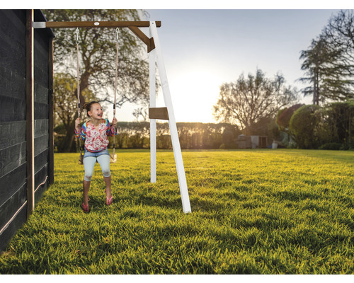 Mädchen schwingt auf einer Holzschaukel im Garten.
