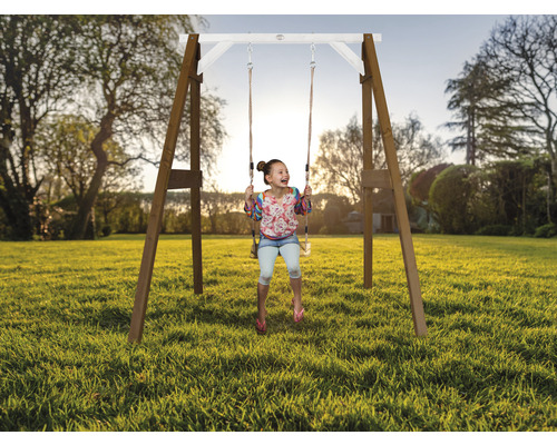 Mädchen schwingt auf einer Holzschaukel im Garten.