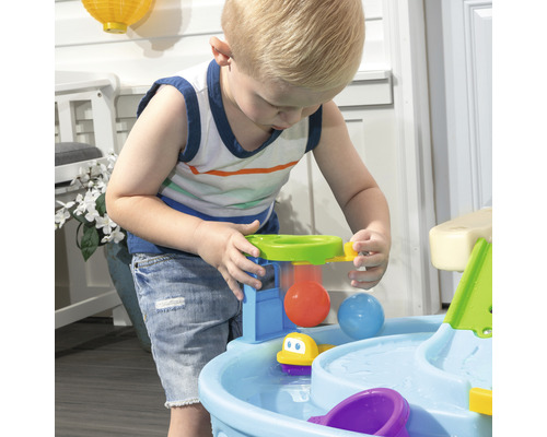 Garçon jouant avec une table de jeu d''eau à l''extérieur.