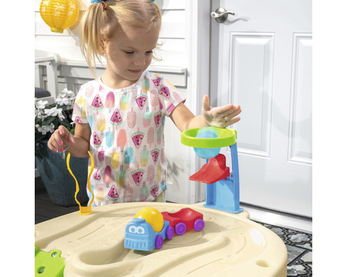 Une fille joue avec une table à sable et à eau avec des accessoires