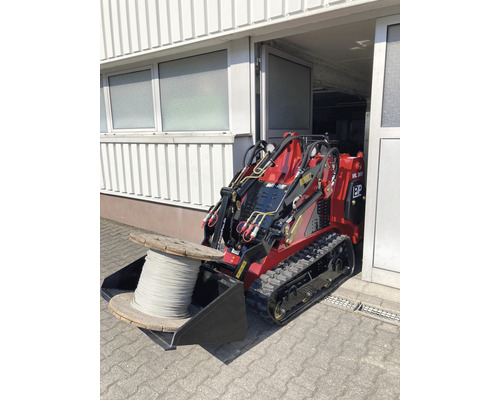 Chargeuse compacte avec touret de câble dans le godet