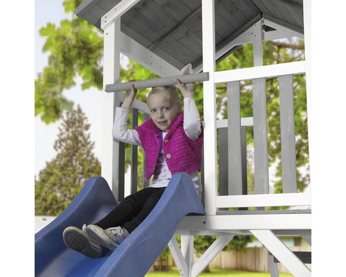 Mädchen auf einer Rutsche eines Spielturms im Garten.