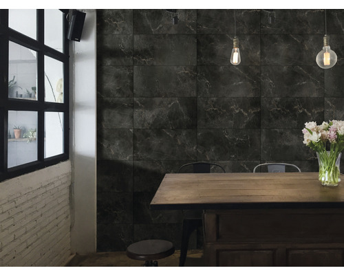 Intérieur avec des carreaux de marbre foncé sur le mur, une table à manger et des chaises.