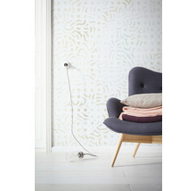 Szene mit gemusterter Tapete, Sessel mit Kissen und Dekorationen sowie einer Lampe auf dem Boden.