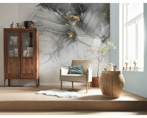 Wohnzimmer mit gemusterten Tapeten, Holzschrank, Sessel und Beistelltisch