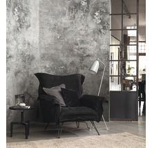 Salon avec fauteuil noir, lampadaire et table d''appoint devant un mur à structure crépie