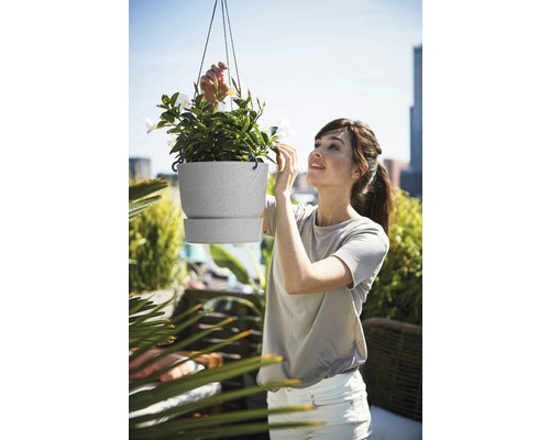 Femme regardant une suspension avec des plantes sur un balcon.