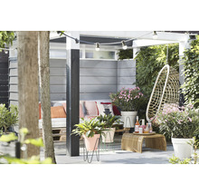 Jardin décoré avec coin salon, fauteuil suspendu, table d''appoint, plantes et guirlande lumineuse.