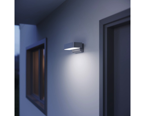 Applique murale moderne pour l''extérieur éclairant un mur de maison à côté d''une fenêtre et d''une porte.