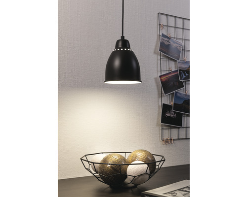 Schwarze Hängeleuchte über einer Schale mit Dekokugeln auf einem Tisch.