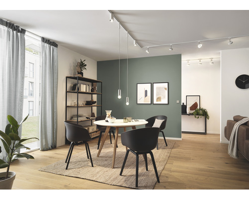 Helles Wohnzimmer mit Esstisch, Stühlen, Regalen und linearem Schienensystem mit Strahlern und Pendelleuchten