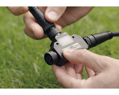 Personne connecte un raccord en T pour un éclairage de jardin basse tension