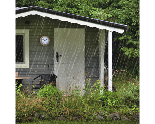 Gartenhaus mit Uhr und Gartenmöbeln im Regen