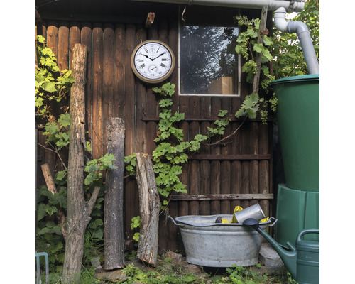 Gartenhaus mit Uhr, Regentonne und Zinkwanne im Garten