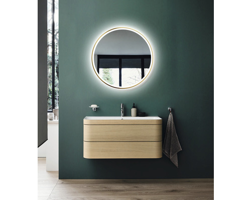 Salle de bains avec un miroir rond lumineux, un meuble-lavabo en bois et des robinetteries