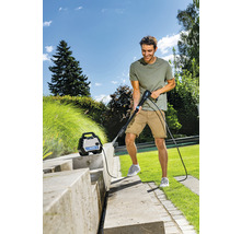 Mann reinigt Steintreppe mit Hochdruckreiniger im Garten.