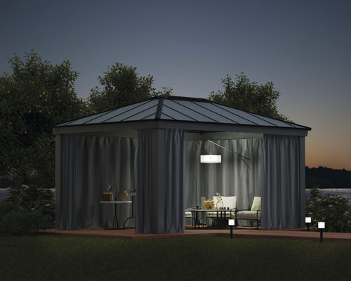 Pavillon mit Vorhängen, Tisch und Stühlen auf einer Terrasse bei Nacht
