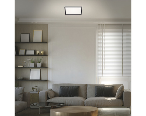 Wohnzimmer mit Sofa, Regalen und quadratischer Deckenleuchte