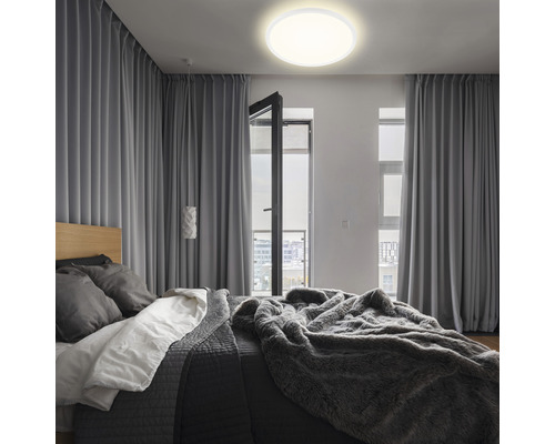 Chambre avec lit, rideaux et plafonnier rond